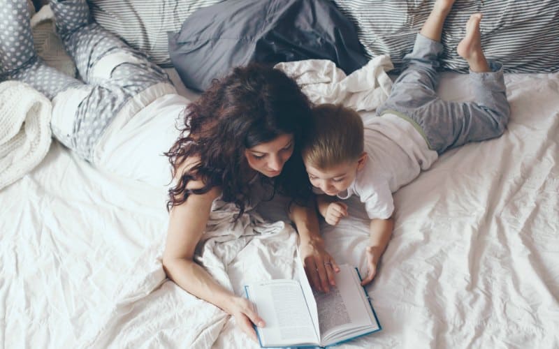 mom who has the feeling of guilt with her little boy reading a book