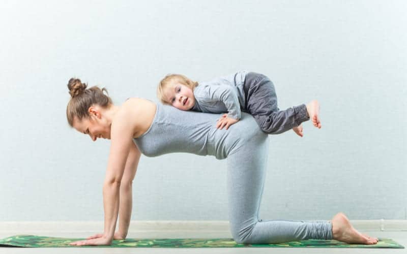 mom working out with child on her back