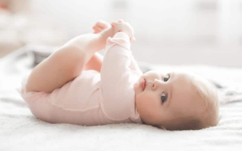 infant in pink onesie looking at camera