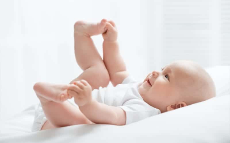 smiling infant holding onto feet