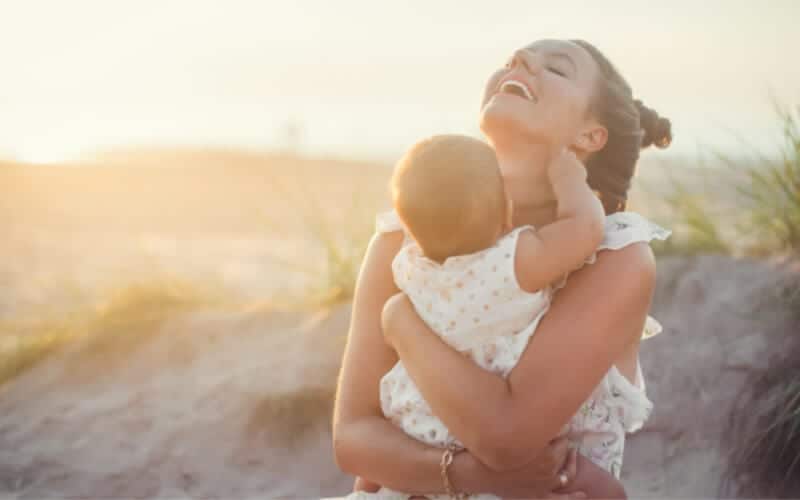 mother on beach holding baby showing the child her love