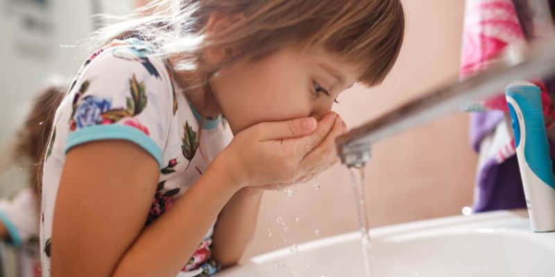 little girl washing her mouth out in the sink