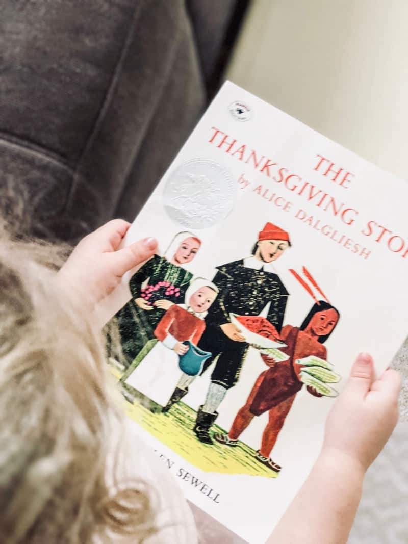 toddler reading a book about the thanksgiving story for kids